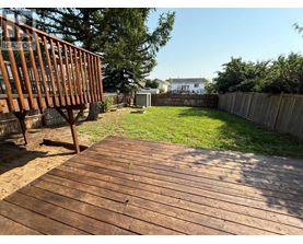 A wooden deck leads to a backyard with a fence and green grass.