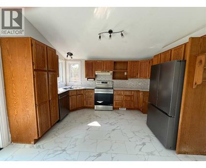 A kitchen with wooden cabinets and a marble floor.