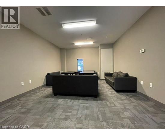 A spacious room with a grey carpet and two black sofas.