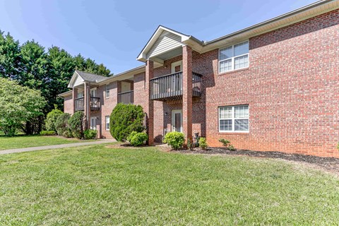 A red brick apartment building with a balcony on the second floor.