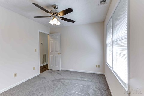 A room with a ceiling fan and a door.