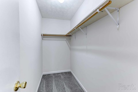 A white hallway with a door on the left and a carpeted floor.