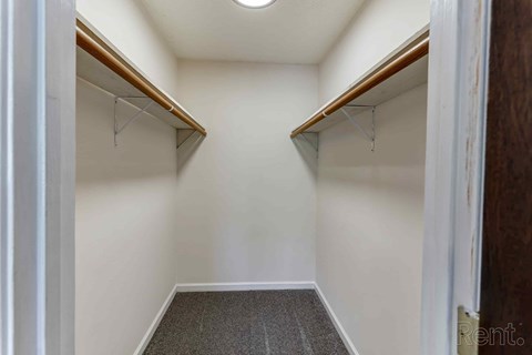 A hallway with a carpeted floor and two wooden shelves on either side.