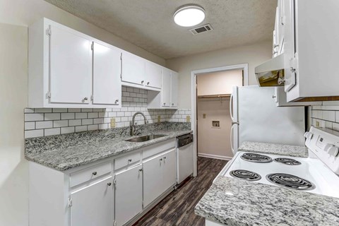 A kitchen with white cabinets and a granite countertop.