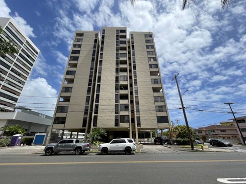 A tall building with a parking lot in front of it.