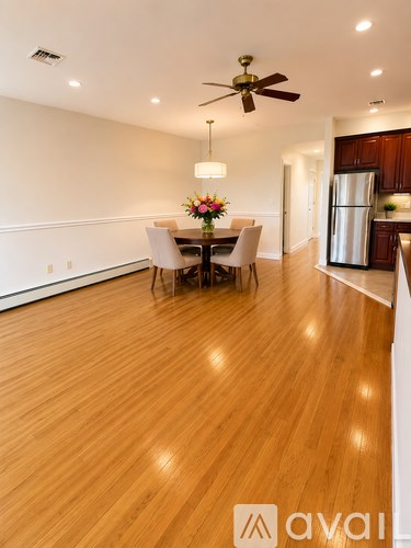 A dining room with a table set for four and a kitchen in the background.