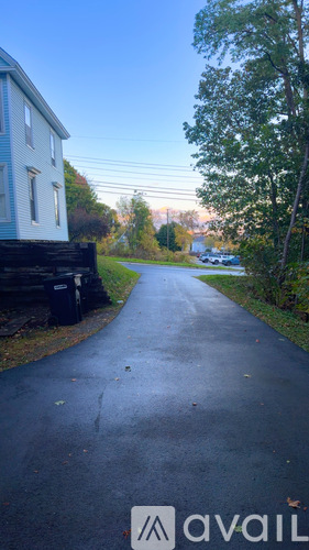 A residential street with a house on the left and trees on the right.