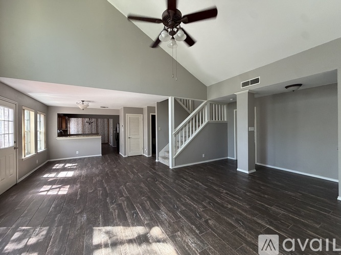 A spacious room with wood flooring and a ceiling fan.