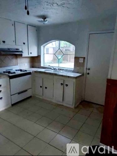 A kitchen with white cabinets and a tiled floor.