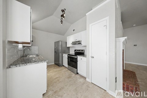 A kitchen with white cabinets and a granite countertop.