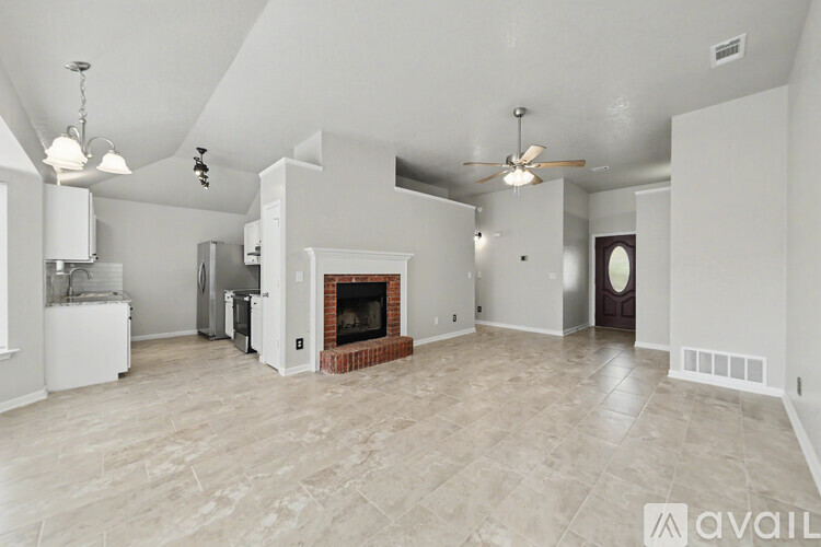 A spacious living room with a fireplace and a ceiling fan.