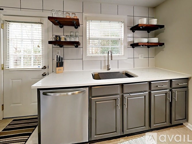 A kitchen with a white counter top and a silver dishwasher.