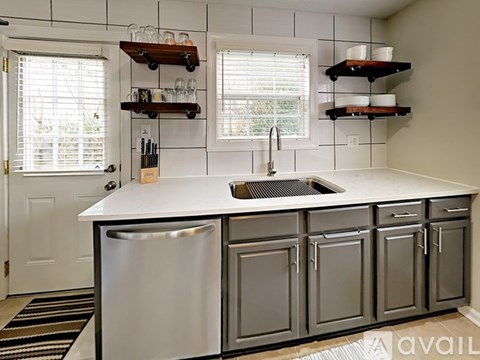 A kitchen with a white counter top and a silver dishwasher.