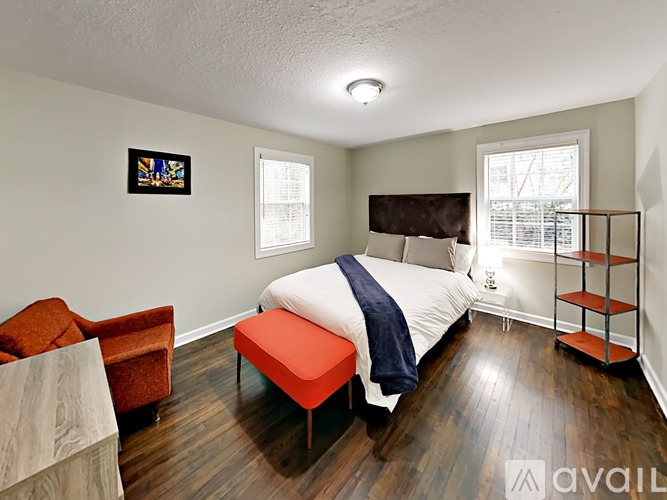 A bedroom with a bed, chair, and shelves.