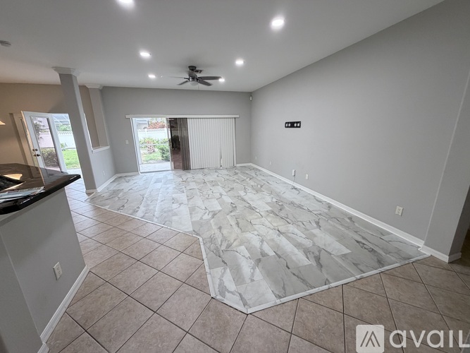 A spacious room with a marble floor and a ceiling fan.