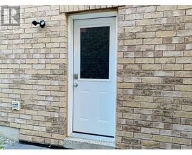 A white door with a window is on a brick wall.