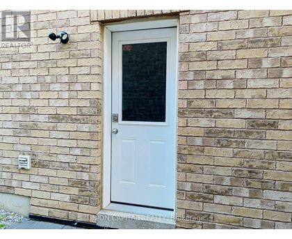 A white door with a window is on a brick wall.