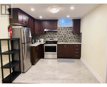 A kitchen with a refrigerator, oven, and sink.