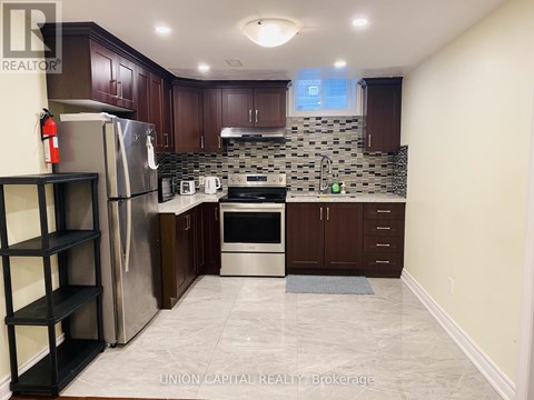 A kitchen with a refrigerator, oven, and sink.