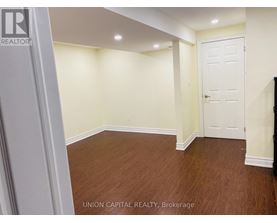 A room with wooden flooring and white walls, with a door on the right side.