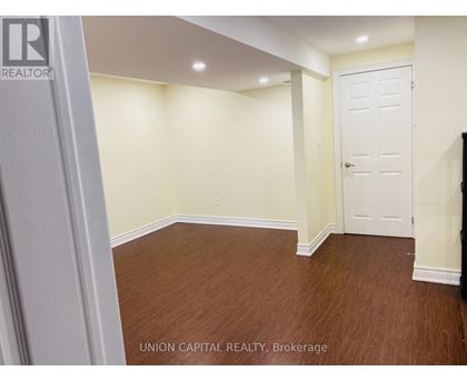 A room with wooden flooring and white walls, with a door on the right side.