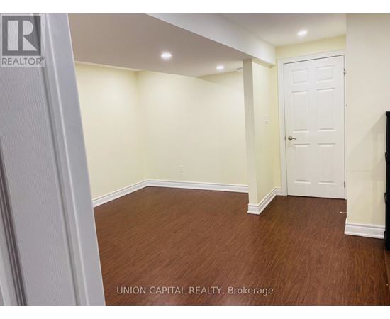 A room with wooden flooring and white walls, with a door on the right side.