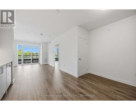 A spacious room with wooden flooring and a large window overlooking a balcony.