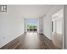 A large, empty room with wooden floors and a view of trees through a glass door.