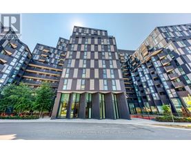 A modern building complex with a glass facade and a central entrance.