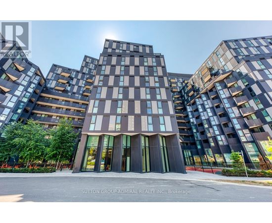 A modern building complex with a glass facade and a central entrance.