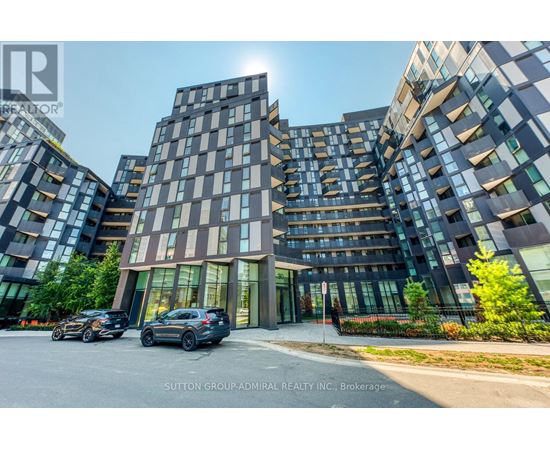 A modern multi-story building with cars parked in front.