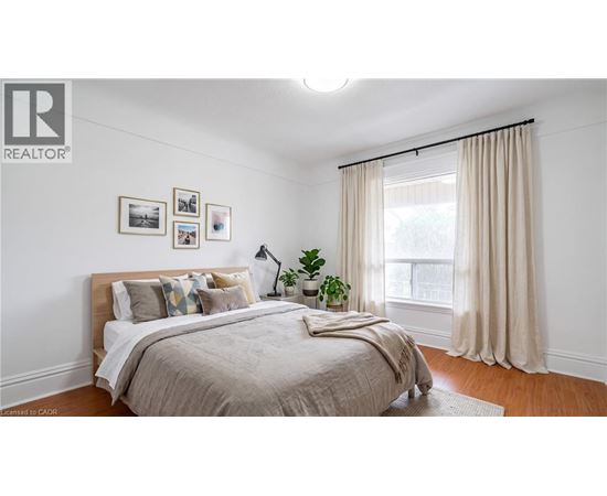 A bedroom with a large bed and a window with curtains.