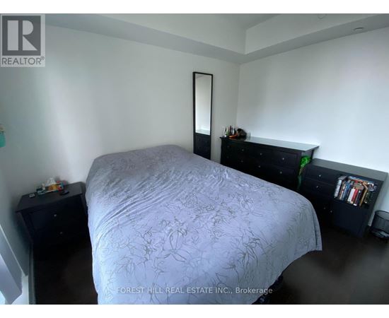 A bedroom with a bed, nightstand, and a dresser with a mirror.