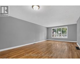 A room with wooden flooring and a window showing trees outside.
