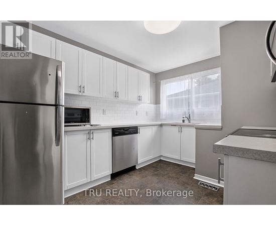 A kitchen with white cabinets and a refrigerator.