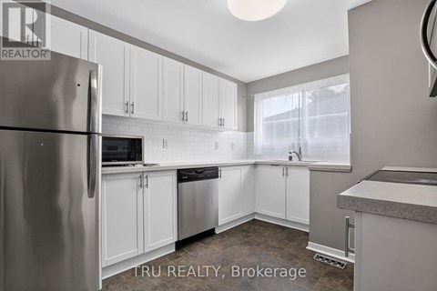 A kitchen with white cabinets and a refrigerator.