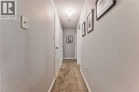 A hallway with a carpeted floor and white walls.