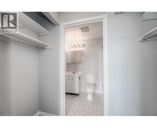 A white bathroom with a toilet, sink, and cabinet.