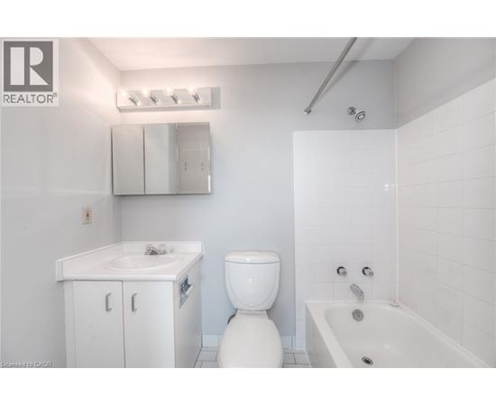 A white bathroom with a toilet, sink, and bathtub.