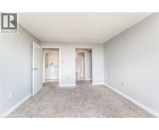 A spacious room with carpeted floor and two open doors leading to other rooms.