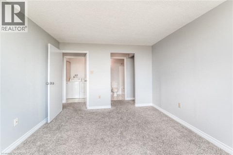 A spacious room with carpeted floor and two open doors leading to other rooms.