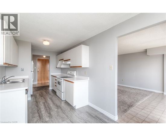 A well-lit kitchen with white cabinets and a wooden door.