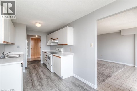 A well-lit kitchen with white cabinets and a wooden door.