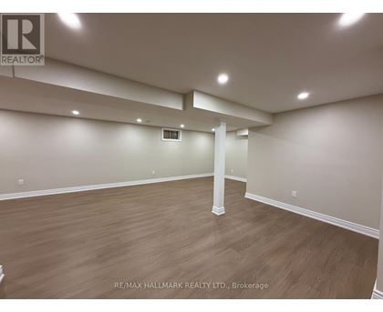 A spacious room with wooden flooring and white walls, with a column in the middle.