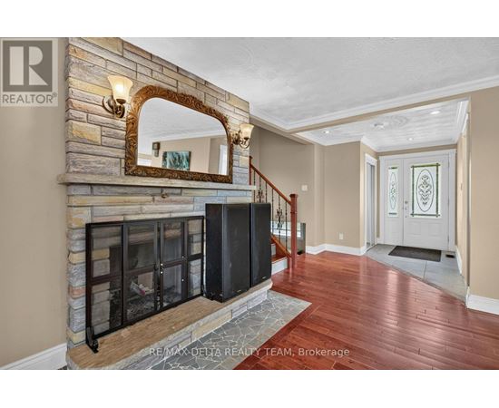 A large mirror is mounted above a stone fireplace in a spacious room.
