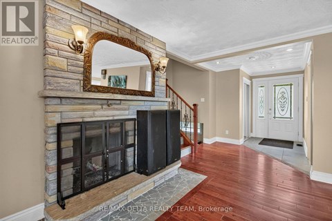 A large mirror is mounted above a stone fireplace in a spacious room.