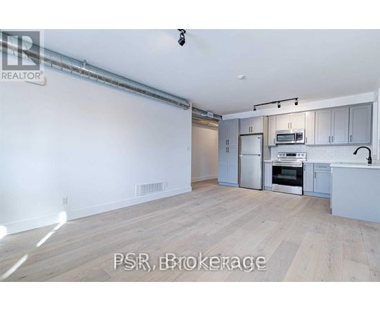 A spacious kitchen with white cabinets and a wooden floor.