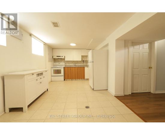 A white kitchen with a refrigerator, oven, and sink.
