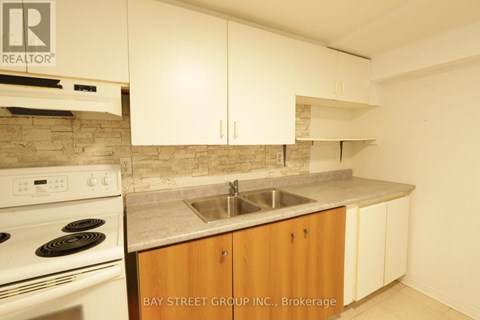 A kitchen with a stove, sink and cabinets.