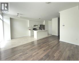 A spacious room with wooden flooring and a kitchen area in the background.